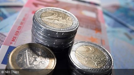 Gestapelte Ein- und Zwei-Euromünzen auf Banknoten