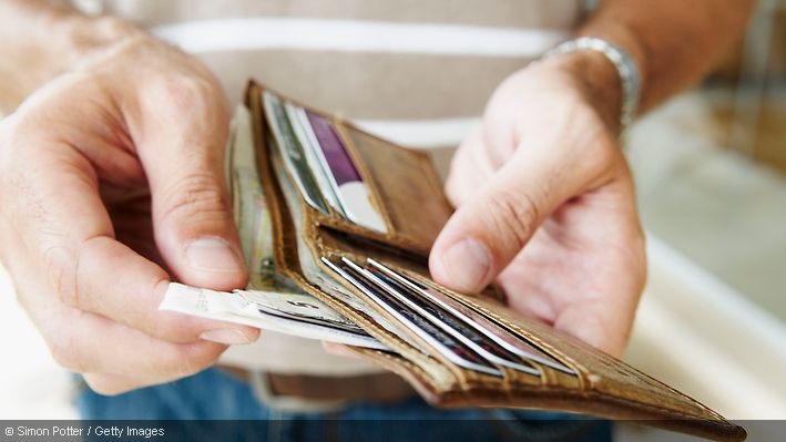 Ein Mann entnimmt Bargeld aus einem Portmonee