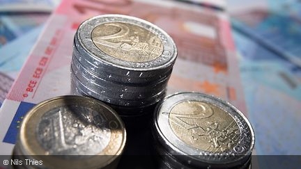 One and Two Euro coins stacked on top of banknotes