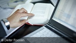 An open book next to a laptop