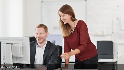 Zwei Personen schauen sich etwas am Computermonitor an.